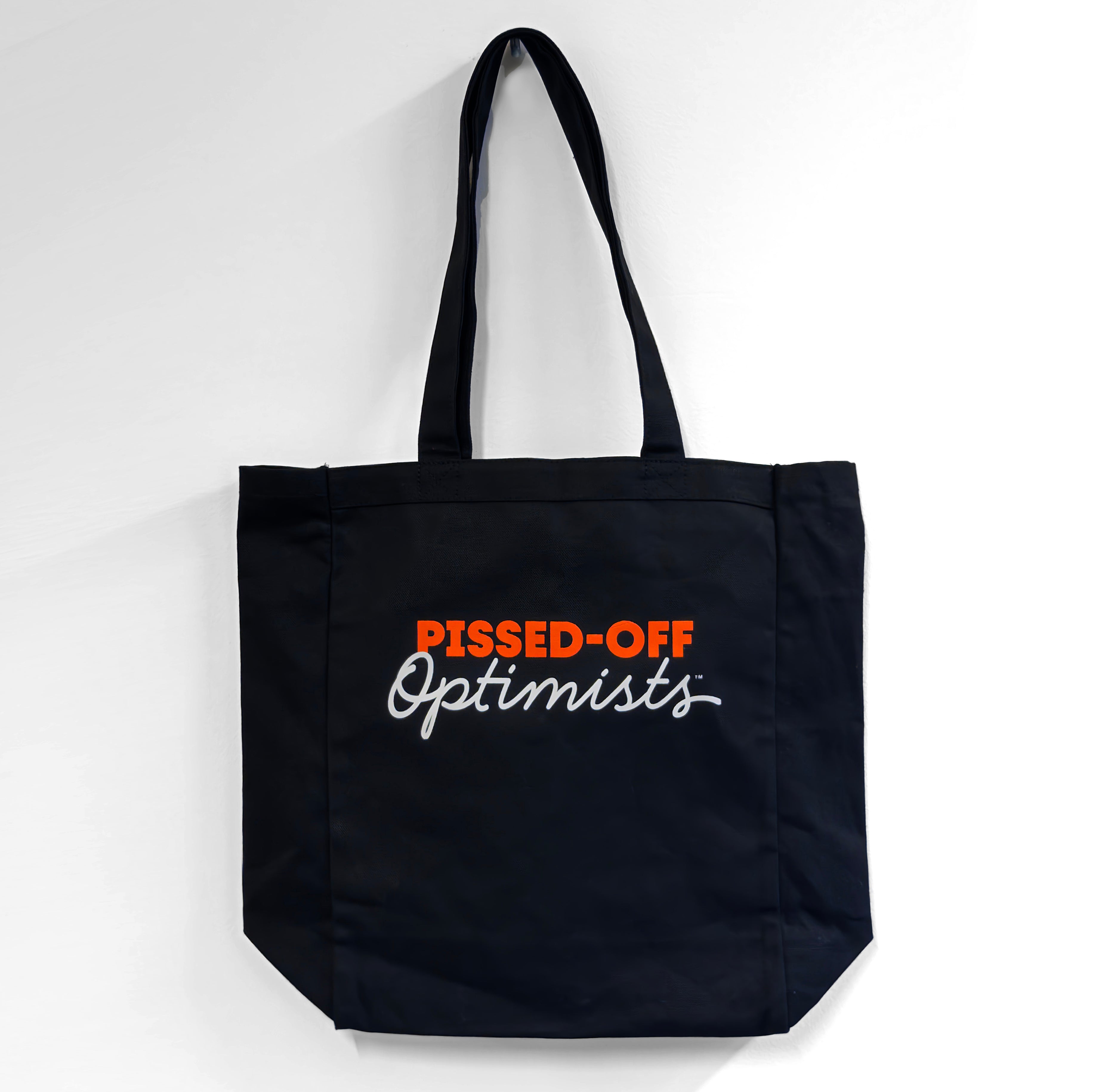 Black tote bag with 'PISSED-OFF Optimists' text on a white background