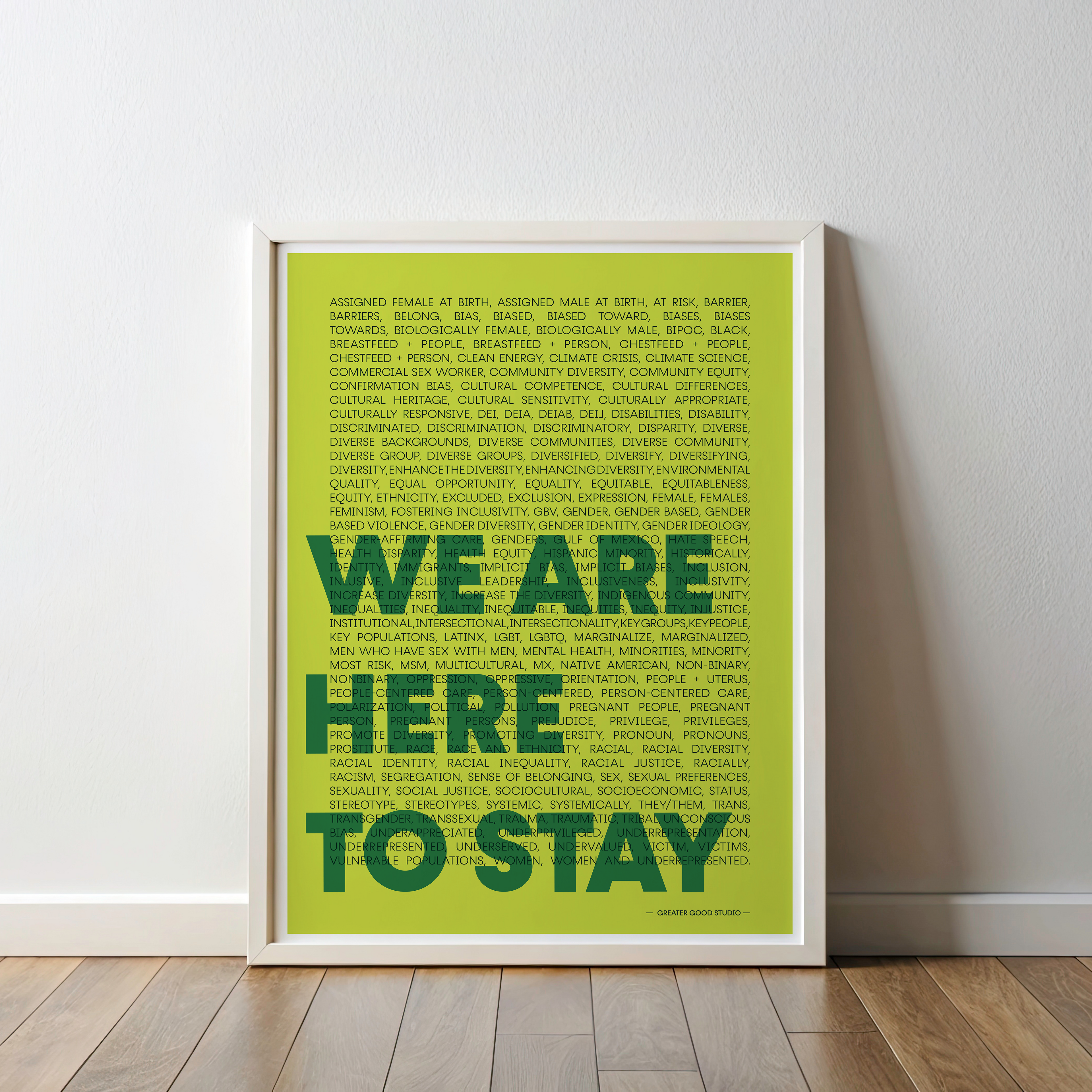 Framed poster with 'WE ARE HERE TO STAY' text on a light green background, leaning against a white wall.